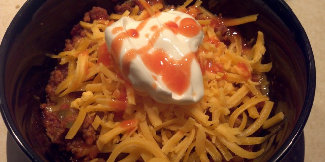 Caveman Chili topped with cheese, sour cream and frank's red hot